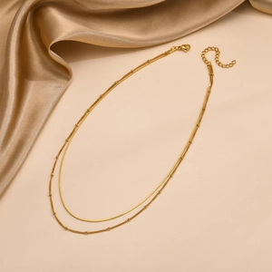 Detail of a layered golden stainless steel snake chain necklace with bead accents