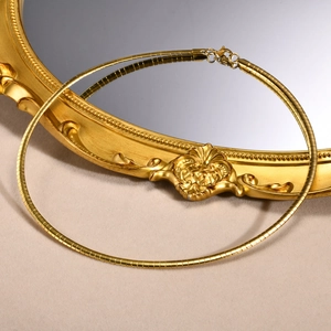 Minimalist gold flat snake chain necklace with lobster clasp on elegant velvet background