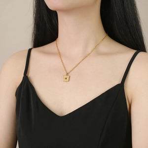 Collier en acier doré avec pendentif étoile en zircon rouge porté sur un mannequin femme