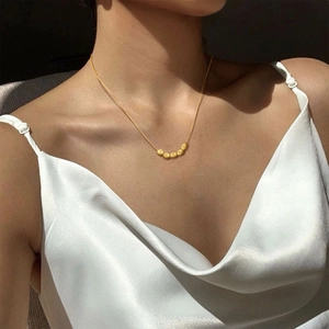 Golden round snake chain necklace with five polished beads worn by a model