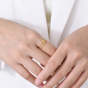 Detail of a double-layered gold heart ring on hand with a minimalist chain design