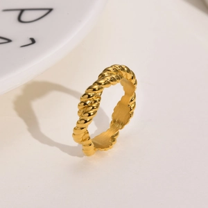 Detail shot of golden twisted rope croissant ring with polished mirror finish on white plate