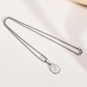 Vue macro du pendentif tournesol ovale en acier inoxydable argenté avec chaîne torsadée