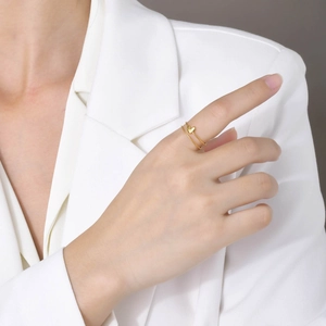 Detail shot of a minimalist double-band gold heart ring on a finger with white suit