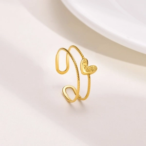 Detailed view of golden double-layer ring with heart charm and beaded texture