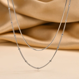 Detail of silver double-layer necklace featuring a fine snake chain and beaded satellite chain