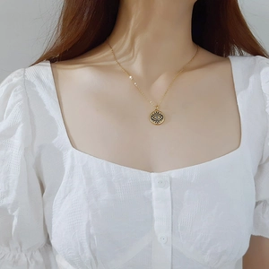Collier mauvais œil en acier inoxydable doré pour femme sur un haut à manches bouffantes