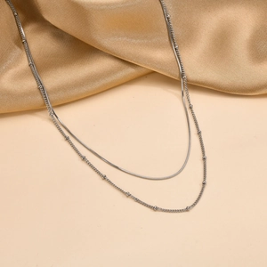 Detail of silver double-layered necklace featuring sleek snake chain and beaded texture