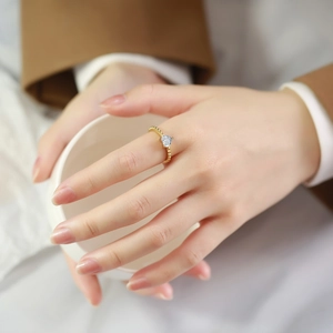 Anello in acciaio dorato con zircone a cuore e fascia a sfere indossato all'indice