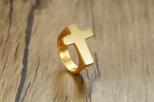 Detail view of the polished golden cross ring on a natural wooden background surface