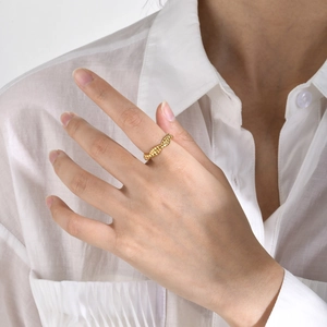 Macro detail of polished golden twisted rope ring worn over white fabric background