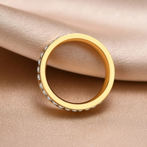 Macro view of gold ring featuring a single row of sparkling crystals on champagne silk
