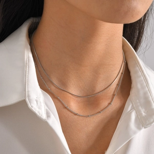 Detail of silver double layer necklace with satellite beads and sleek snake chain on neck