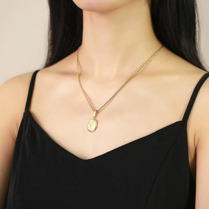 Gros plan d'un pendentif rose ovale doré sur une chaîne torsadée porté par un modèle