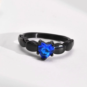Close-up of black segmented ring featuring a heart-shaped blue zircon stone in claw setting