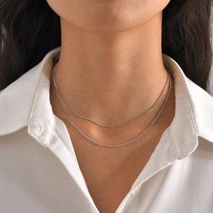 Detail view of double-layer silver snake chain necklace worn on professional model