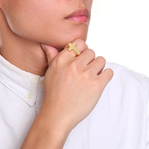 Close-up of a gold cross-shaped cast ring worn by a male model in a white shirt