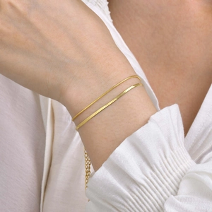 Close-up of double-layer 18K gold snake and link chain bracelet set on female wrist
