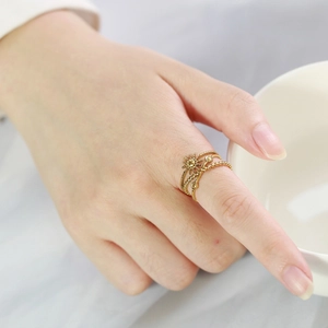 Close-up of golden multi-layer ring featuring celestial star and sun motifs on finger
