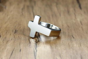 Polished stainless steel cross ring detail showing mirror-like metallic surface on wood