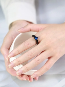 Detail of gothic black metal ring featuring a brilliant blue heart-shaped gemstone