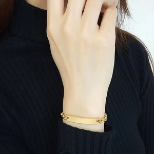 Dettaglio del bracciale a catena in acciaio dorato con barra curva indossato al polso