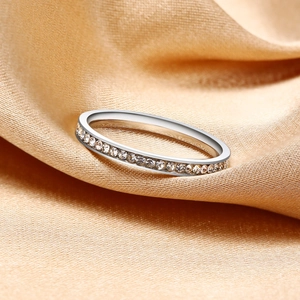 Macro detail of silver ring with pave-set zircons on elegant golden silk fabric