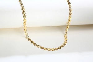 Detailed view of golden leaf-shaped necklace links with intricate engraved textures