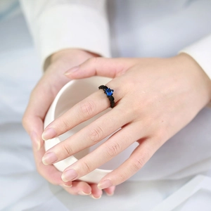 Gothic black heart ring with blue zircon gemstone on a model holding a white cup