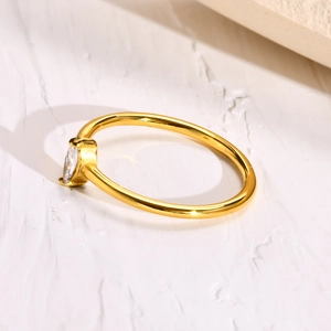 Minimalist gold plated ring with marquise-cut zircon on artistic white texture background