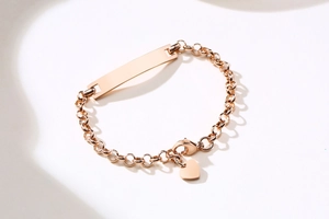 Dettaglio del bracciale a maglie oro rosa con barra curva lucida e ciondolo a cuore