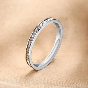 Macro detail of silver eternity ring with zircon stones on champagne silk background
