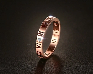 Detailansicht eines roségoldenen Rings mit römischen Ziffern und Zirkonia-Steinen