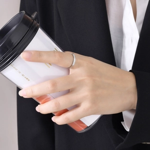 Gros plan d'une bague minimaliste en argent sertie de zircons avec tasse de café