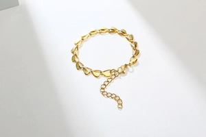 Close-up of golden stainless steel heart-shaped links with brushed metal texture