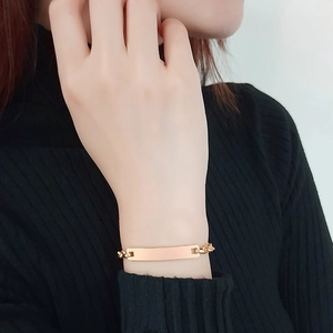 Primo piano di un bracciale a barra in oro rosa lucido da donna indossato su un polso