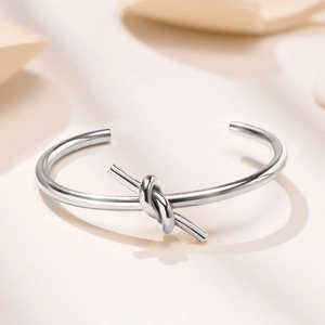Macro view of polished silver knot bracelet featuring a minimalist open-ended design