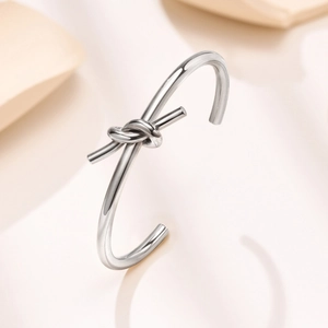 Detailed close-up of polished silver knot cuff bracelet in a minimalist style