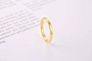Close-up of a minimalist gold-plated stainless steel ring on a white paper background