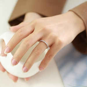 Detailed view of a slender stainless steel ring with pavé-set zircons on a finger