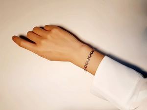 Close-up of a rose gold leaf-shaped link bracelet worn on a female wrist in detail