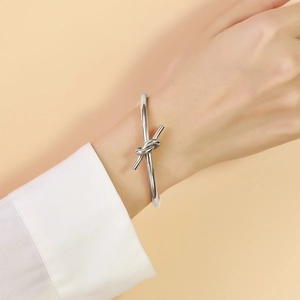 Detail of silver knot cuff bracelet in polished finish worn on a white shirt cuff