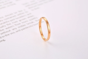 Close-up of a minimalist rose gold plain ring with mirror polish finish on a book