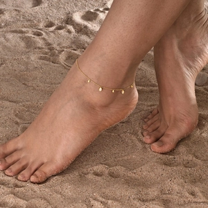 Elegant gold stainless steel anklet with water drop zircon tassels on a sandy beach