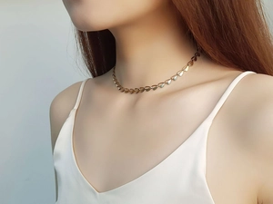 Detailed view of elegant gold leaf-link choker necklace on a model's collarbone