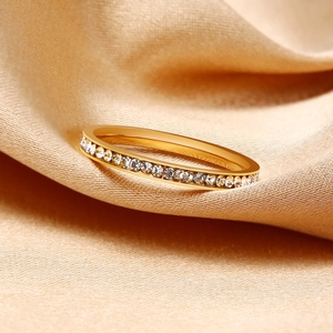 Close-up of gold slim band ring with sparkling cubic zirconia on champagne silk
