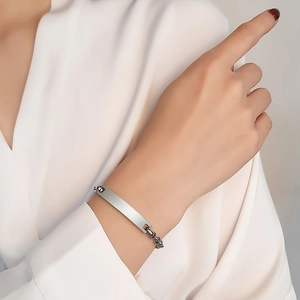 Dettaglio di un bracciale a barra minimalista in acciaio inossidabile argento sul polso