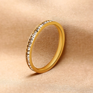 Detail of slim gold stainless steel ring with zircon inlays on champagne silk fabric