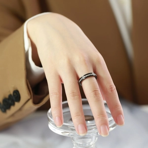 Detail of a thin black titanium ring with white cubic zirconia worn on a finger