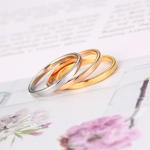 Detailed view of minimalist silver, gold and rose gold rings stacked on a magazine